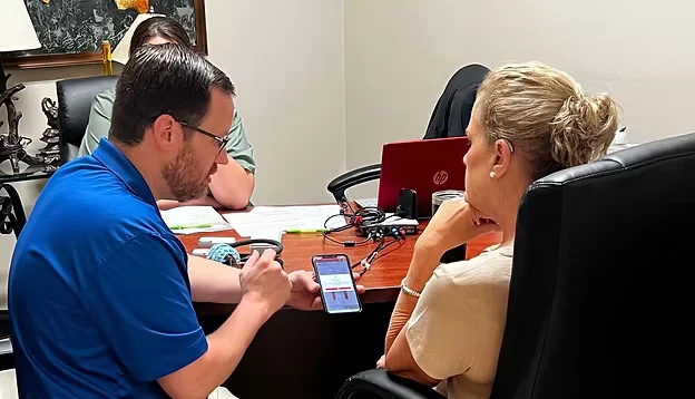 Hearing specialist showing information on a phone to a patient during consultation