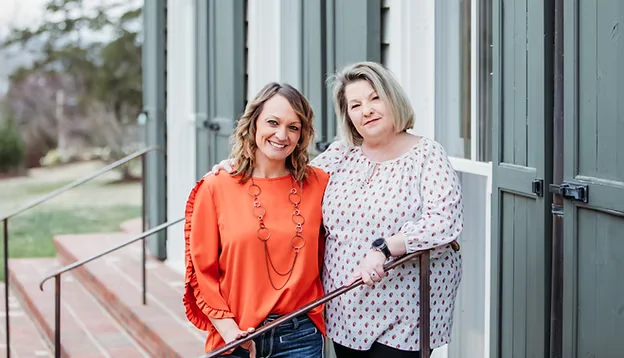 Two staff members standing together outside the clinic building smiling