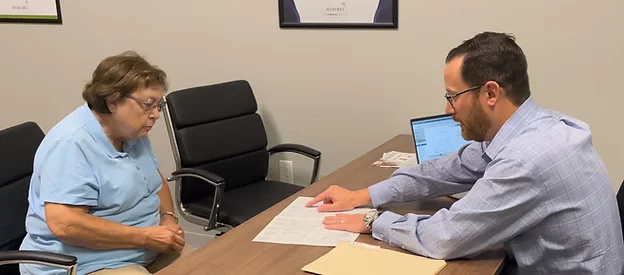 Hearing specialist reviewing paperwork with an older patient during a consultation
